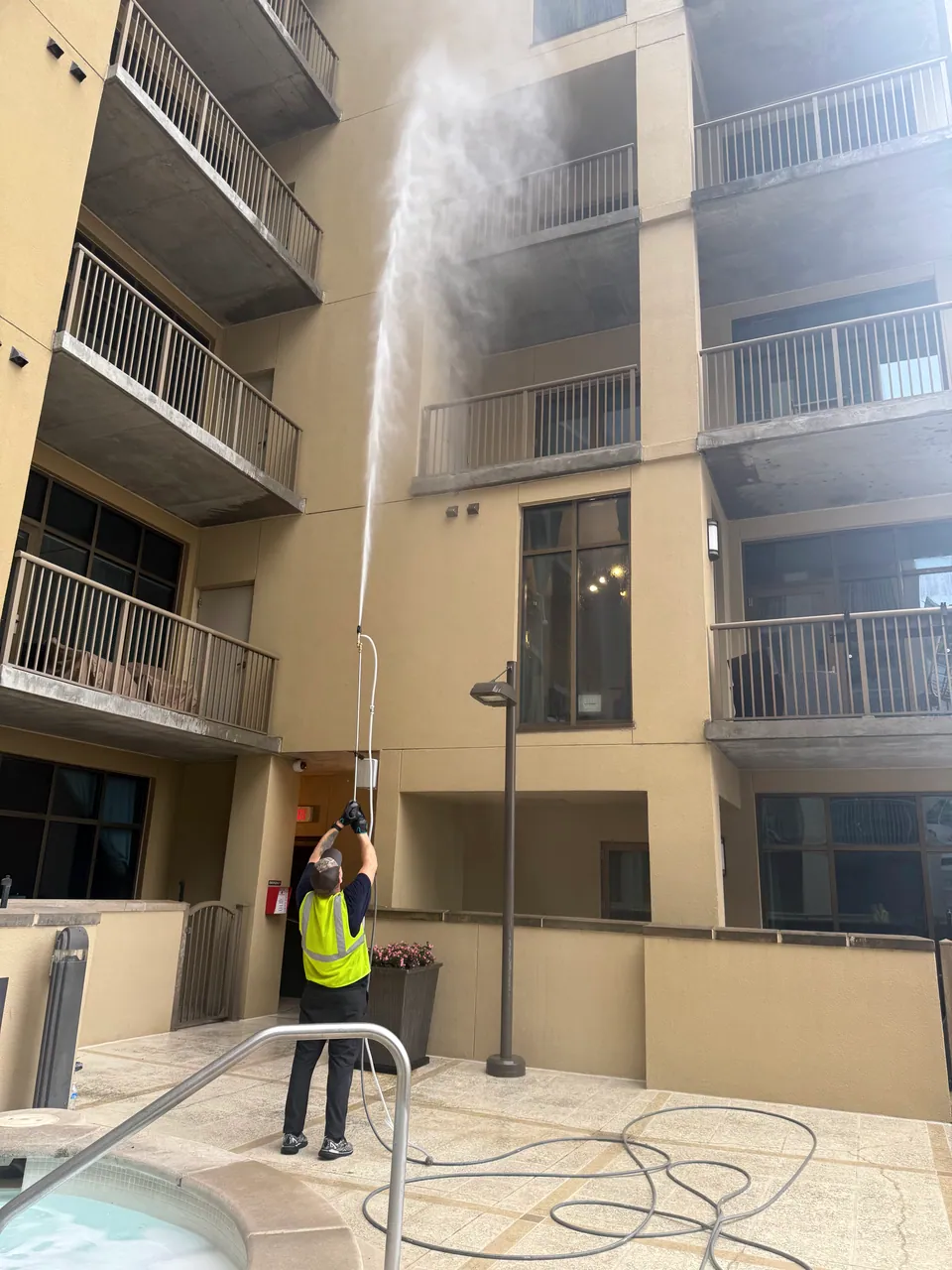 Operator directing water spray up the exterior of a multi-level building