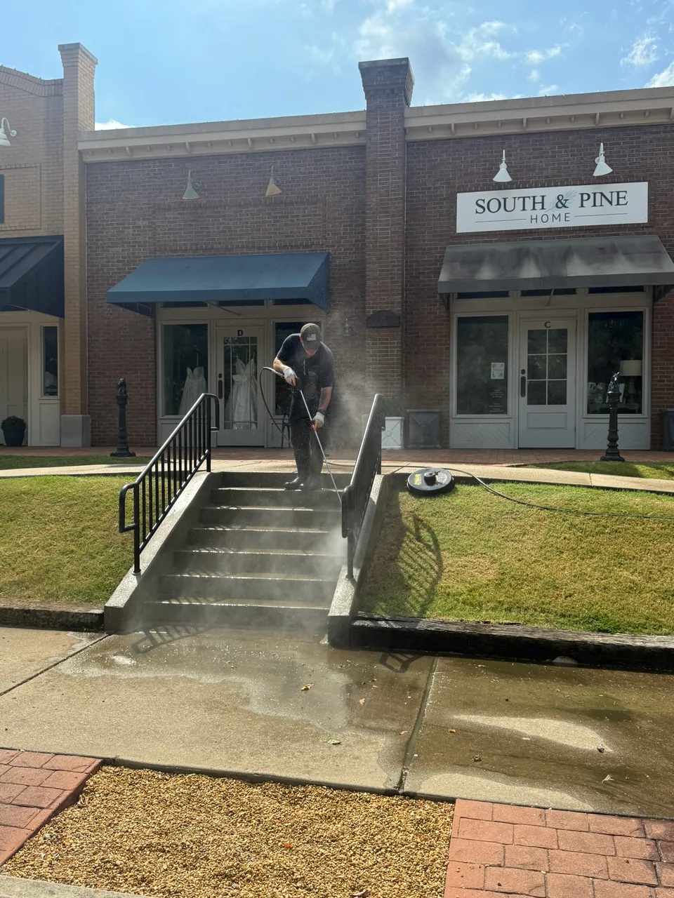 Pressure washing in progress on storefront steps and the entrance approach